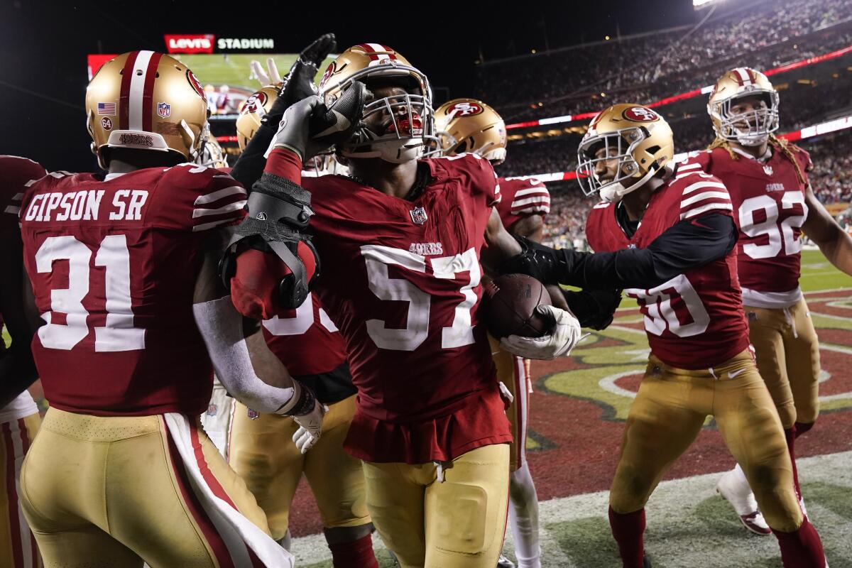 San Francisco 49ers linebacker Dre Greenlaw celebrates with teammates after intercepting a pass against the Packers.