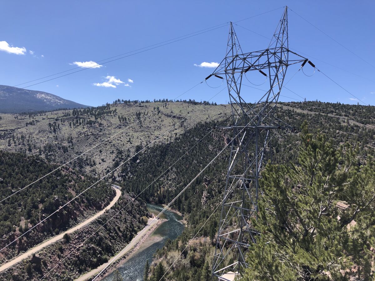 Electric transmission lines on a mountainous landscape, with a river below
