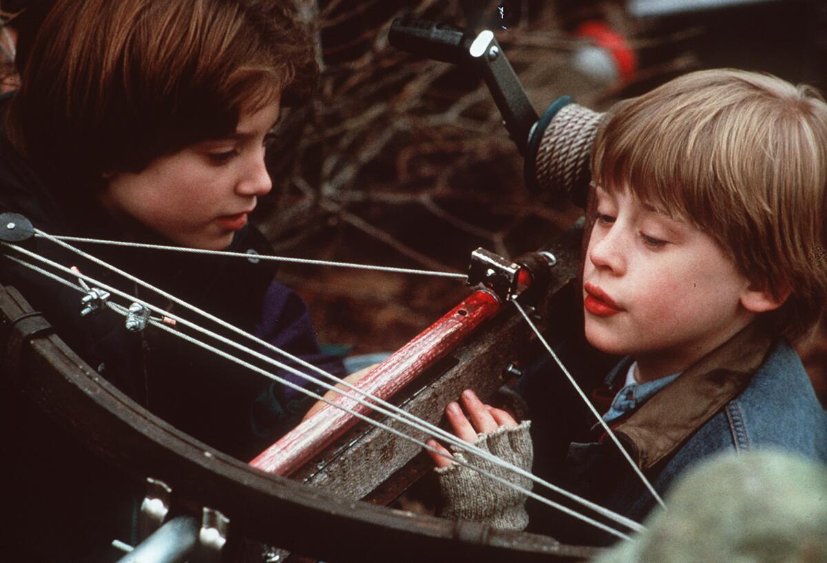 Two young boys look at a crossbow.