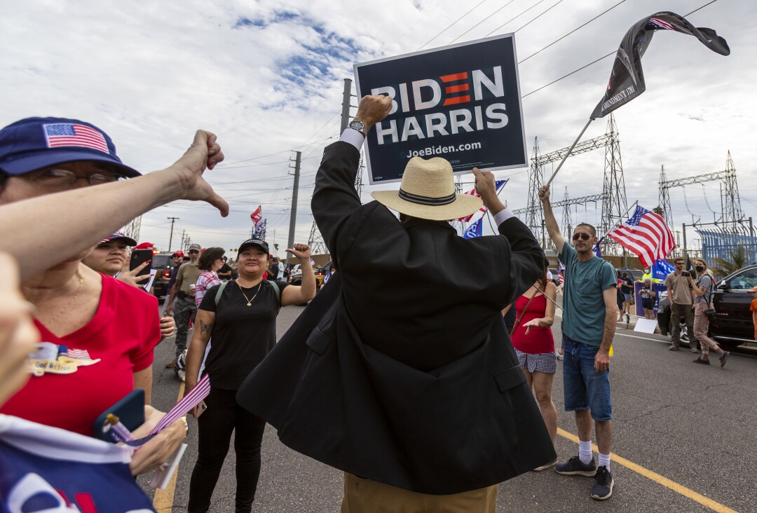 Ron Russ, a supporter of Joe Biden, gets a thumbs-down as he walks through a pro-Trump crowd in Phoenix.