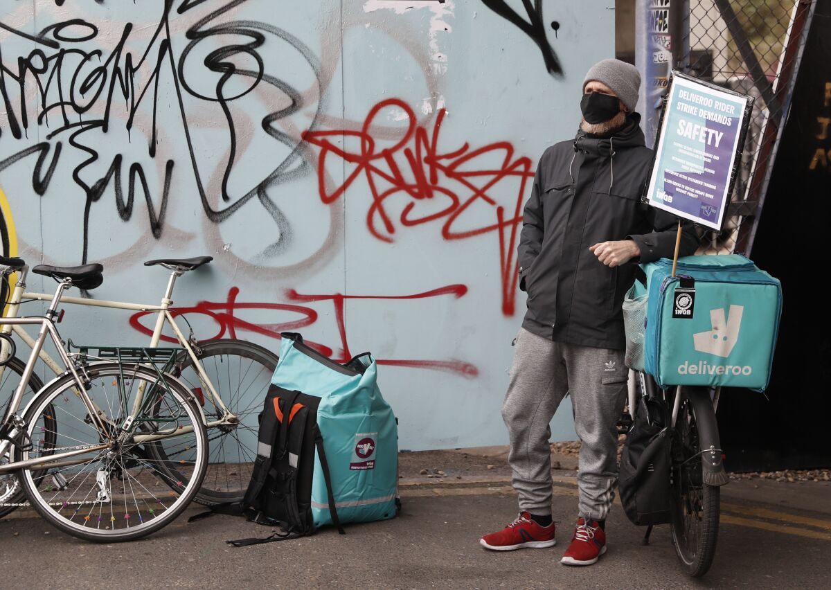FILE - A gig economy ridersfor app-based meal delivery platform Deliveroo takes part in a demonstration, near the company headquarters in London, Wednesday, April 7, 2021. The European Union unveiled plans to improve conditions for the growing number of gig economy workers that could reclassify some as employees who must earn benefits, the latest setback for digital platforms that rely on independent contractors to deliver food and offer rides. (AP Photo/Alastair Grant, File)