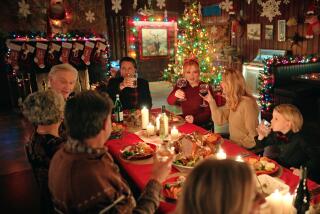 A group of people gather around a holiday table for dinner surrounded by Christmas decorations.