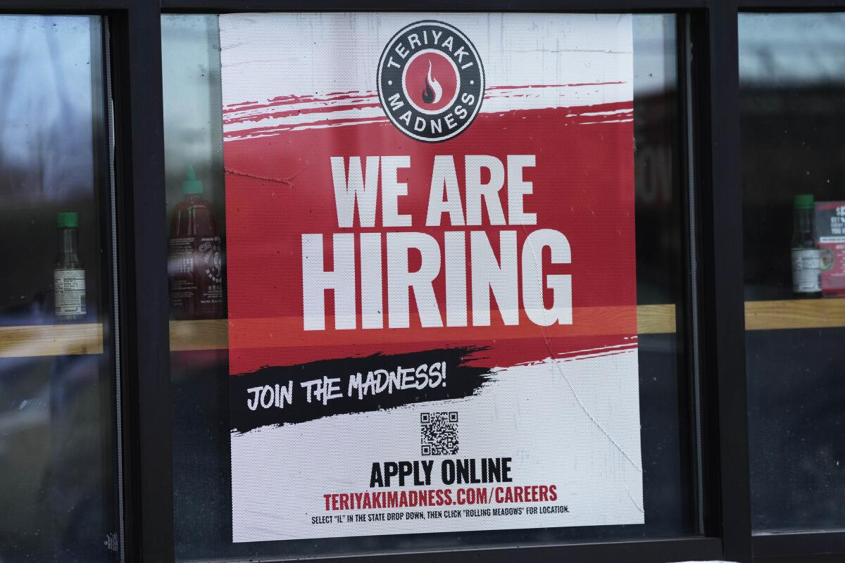 A hiring sign is displayed at a restaurant