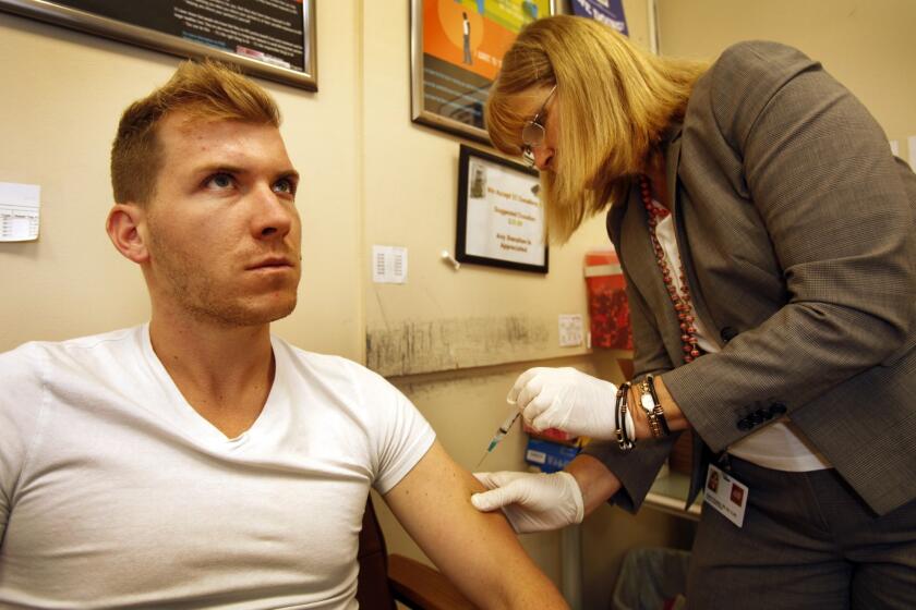 Dylan Cantrell, 27, from West Hollywood focuses as nurse Karen Haughey administers his meningitis vaccination.