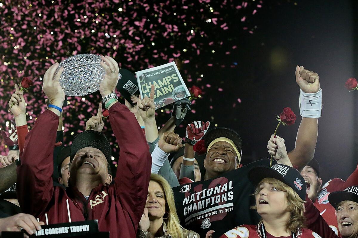 Florida State Coach Jimbo Fisher hoists the crystal BCS trophy overhead during the postgame ceremony after winning the national title with a 34-31 victory over Auburn.