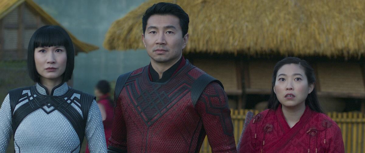 A man in a red outfit is flanked by two women in traditional Chinese dress 