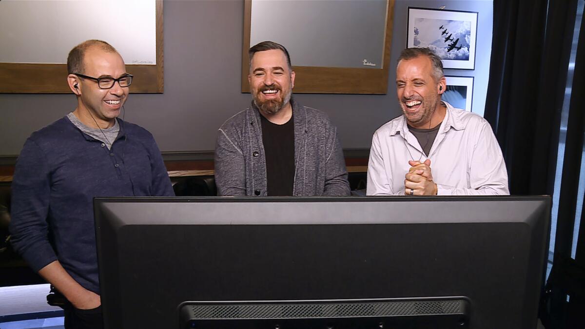 Three men laughing at a TV monitor in the truTV series "Impractical Jokers."