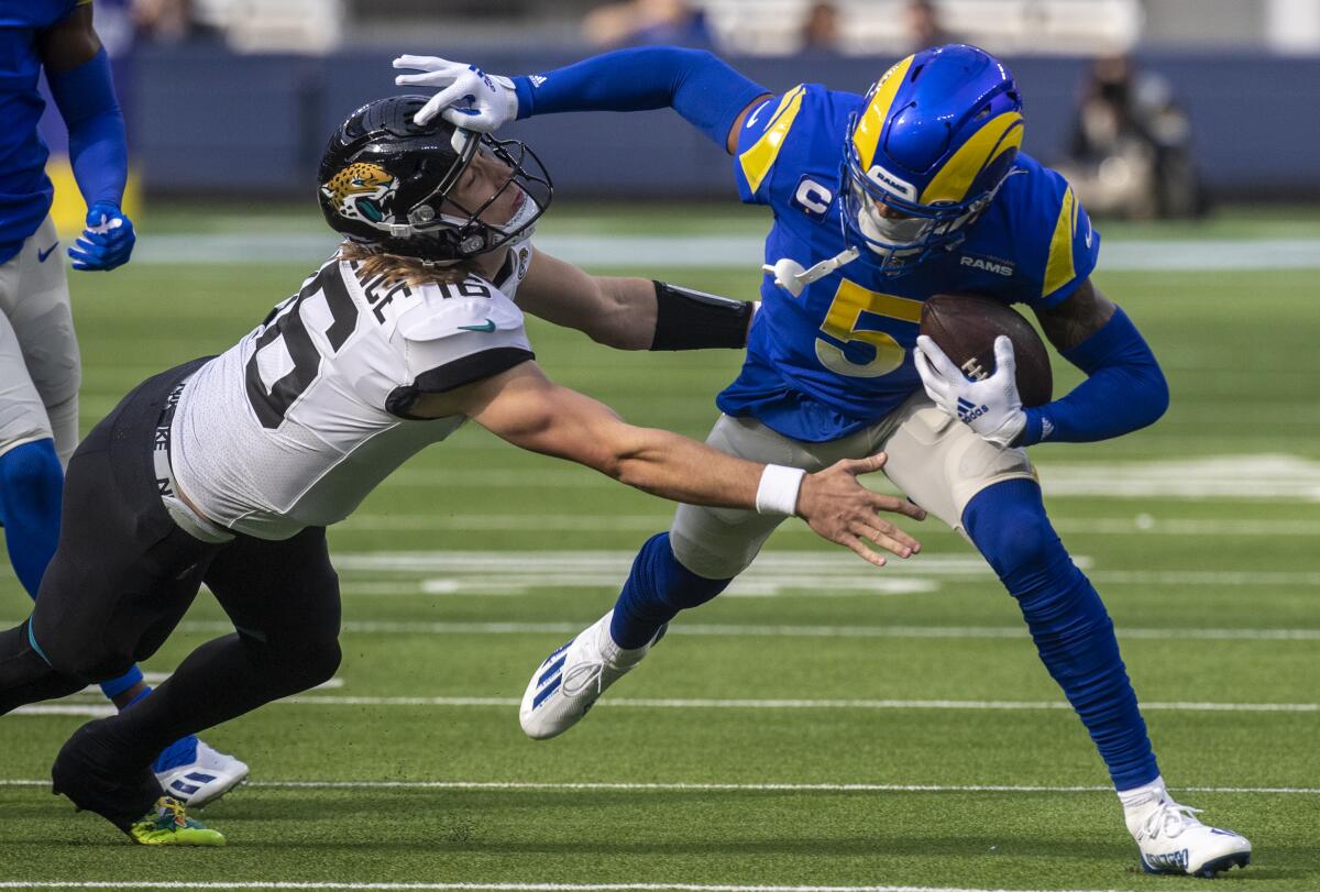 Rams cornerback Jalen Ramsey fends off Jaguars quarterback Trevor Lawrence.