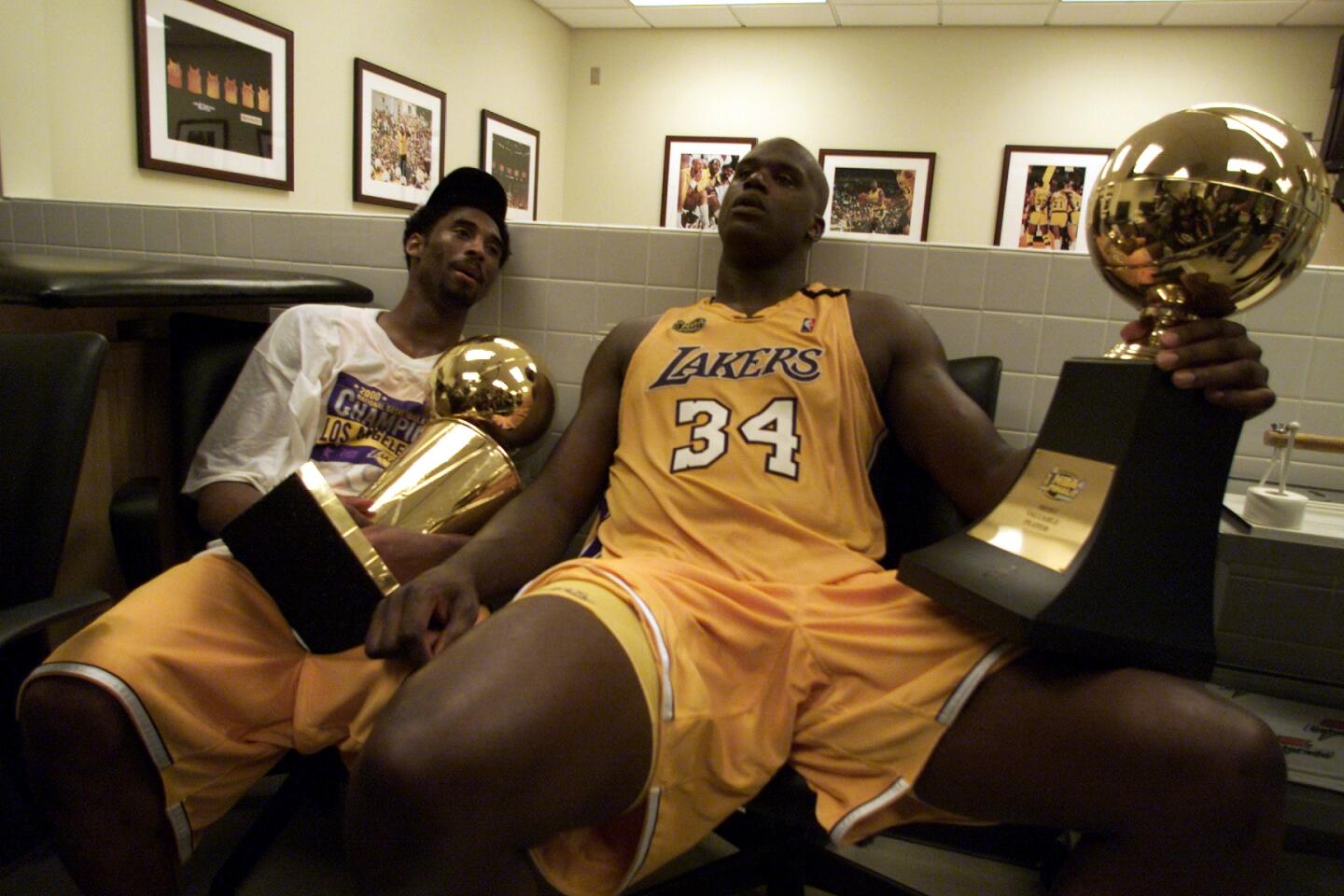 Kobe Bryant, left, and Shaquille O'Neal sit after winning their first title, holding the championship and Finals MVP trophies, respectively.