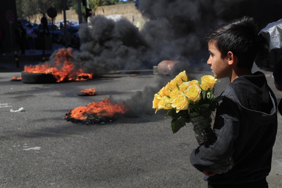 A Syrian boy watches protesters burn tires during a protest in Beirut