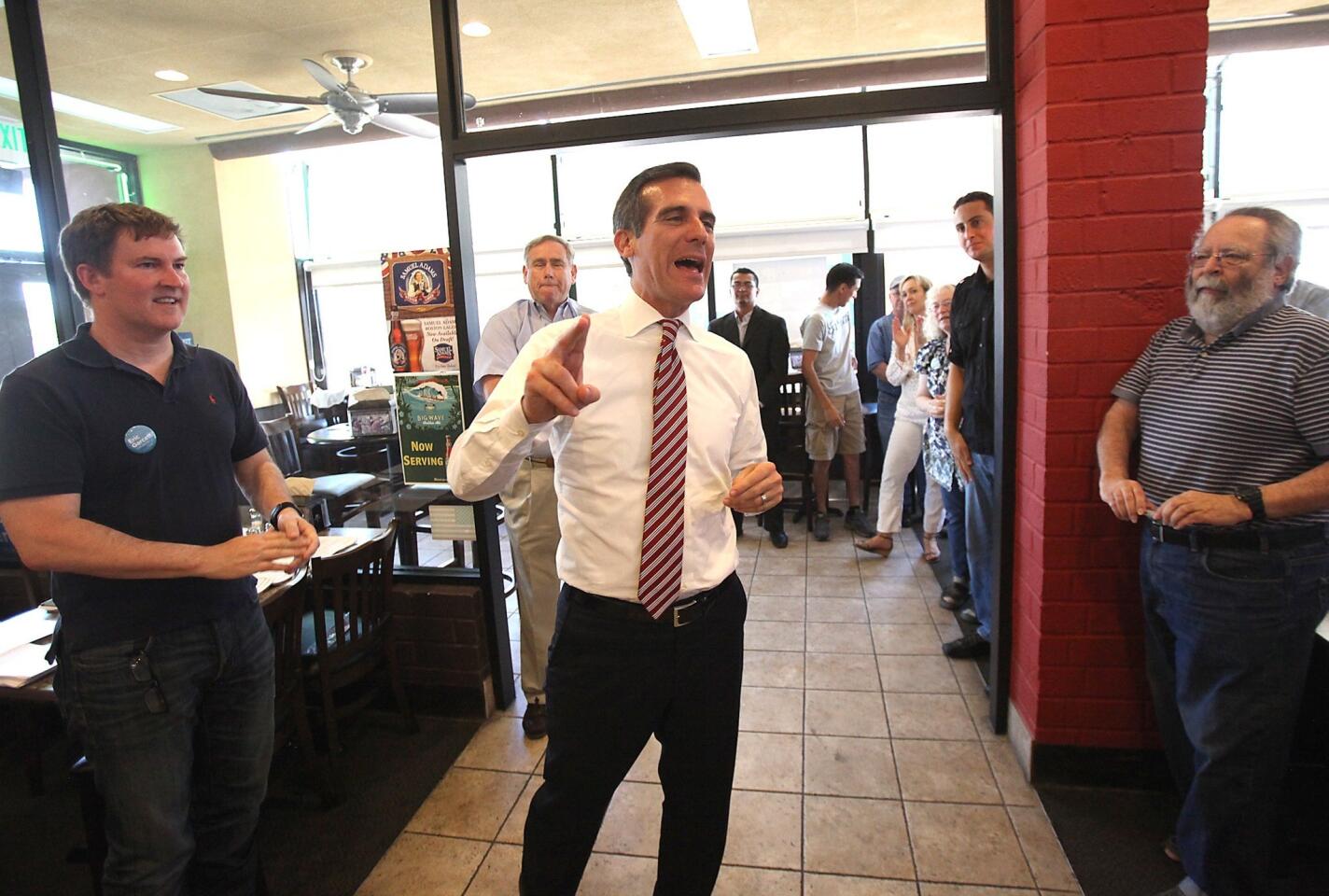 Eric Garcetti, center, speaks with supporters and campaign volunteers, including former mayoral candidate Kevin James, left, at a Straw Hat pizza parlor in Chatsworth.
