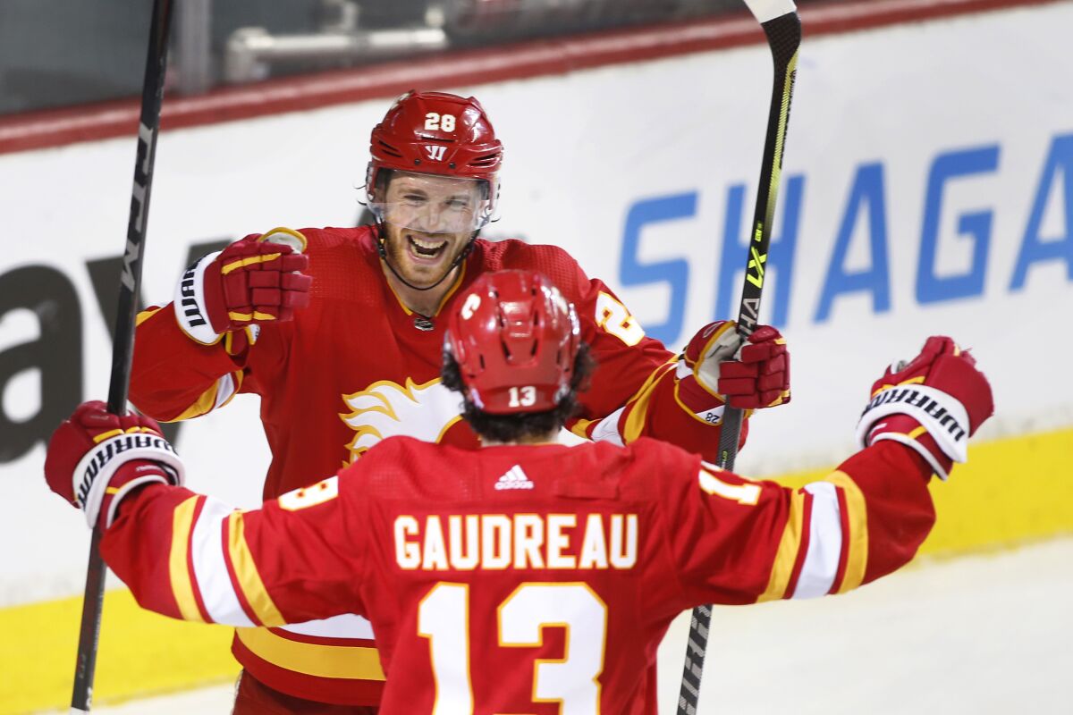 Calgary Flames left wing Johnny Gaudreau (13) celebrates his hat-trick goal against the Tampa Bay Lightning with Elias Lindholm during the third period of an NHL hockey game Thursday, March 10, 2022, in Calgary, Alberta. (Larry MacDougal/The Canadian Press via AP)