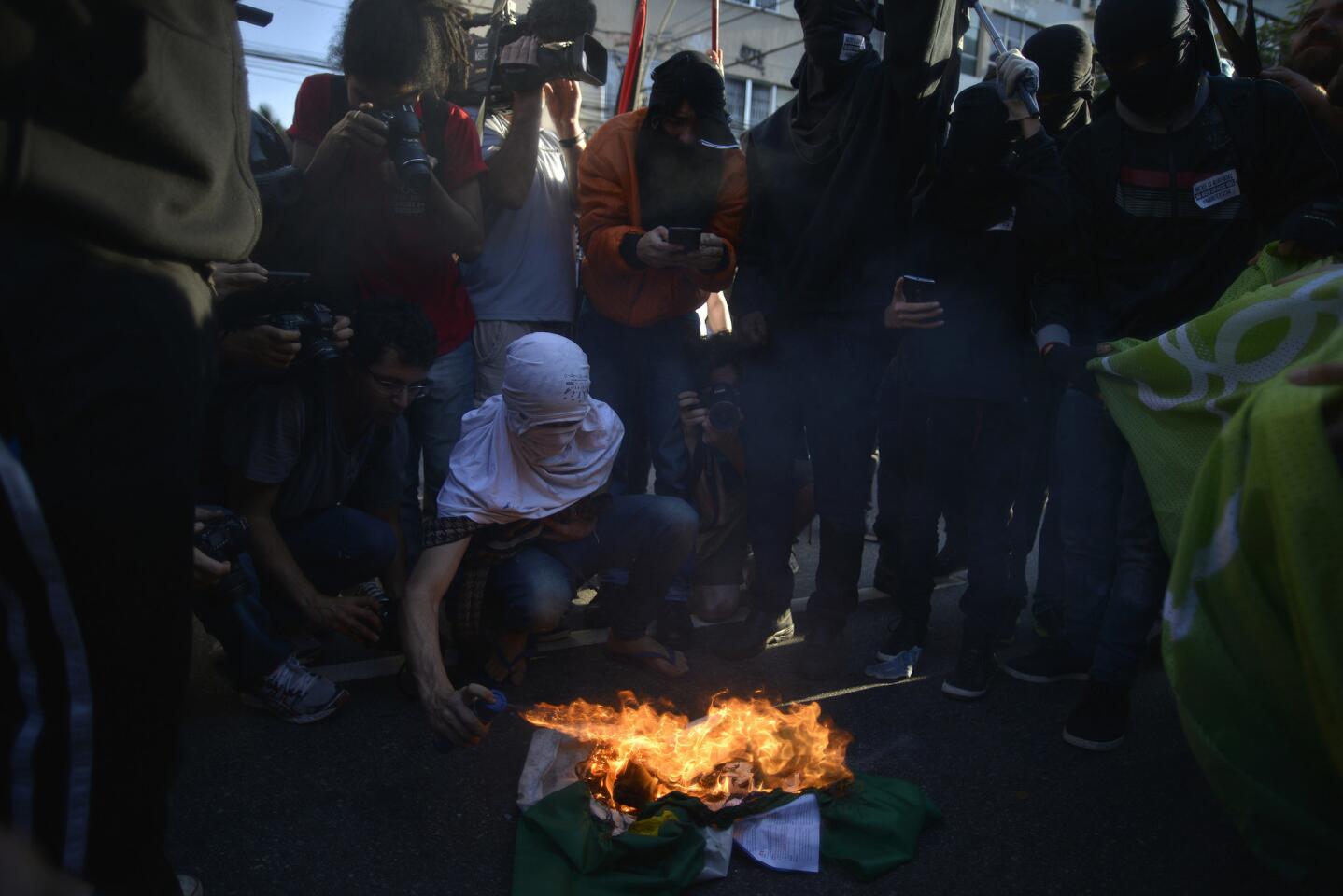 Manifestantes contra los Juegos Olímpicos Río 2016 queman una bandera en la plaza Sans Pena en Tijuca, al norte de Río de Janeiro (Brasil). Los manifestantes marcharon hasta calles cercanas al Estadio do Maracaná, donde policía militar brasileña dispersó las protestas.