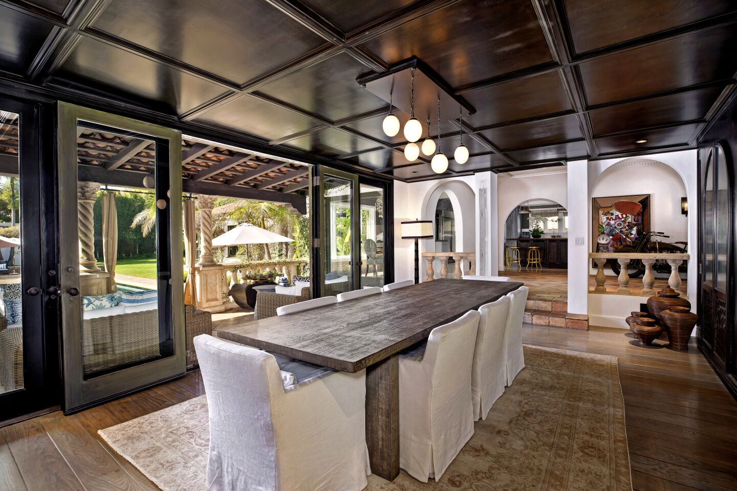 Dark coffered ceilings top the dining room, which opens to a covered patio.