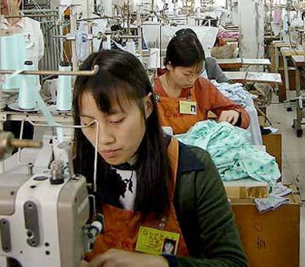 Two Chinese garment workers, Ping Qiu-xia, 20, and Yu Jian-fen, 22, both from Sichuan province, work on an order for Wal-Mart in Germany at the Gladpeer Garment Factory in the southern Chinese city of Dongguan, about 60 miles northwest of Hong Kong.