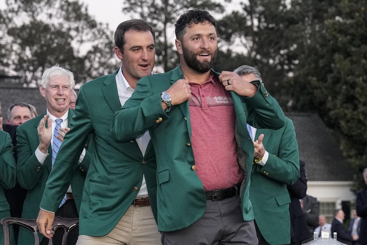 Scottie Scheffler puts the green jacket on Jon Rahm after the Spaniard's win at the Masters.