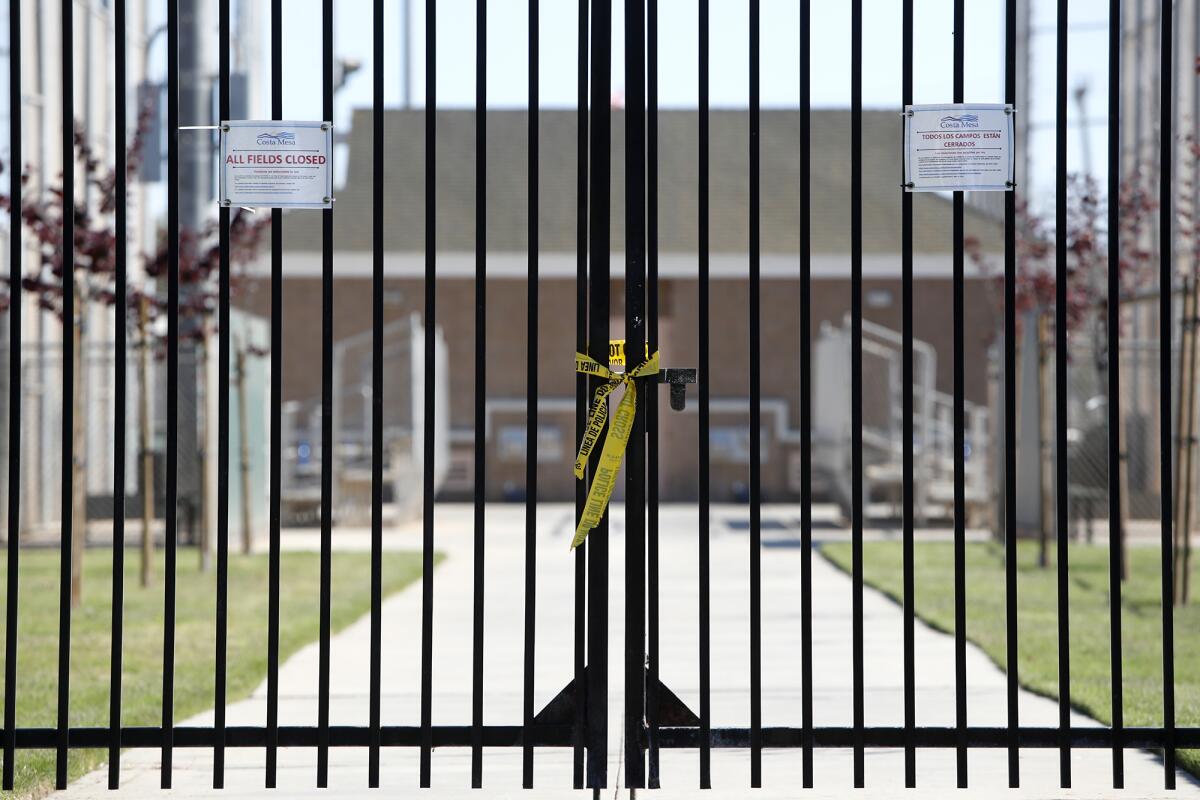 Closure notices, one in English and the other in Spanish, are posted on the north gate at TeWinkle Athletic Complex in Costa Mesa on Saturday. Local PONY baseball leagues are sidelined by the coronavirus and are unsure if they will be able to resume play at all this season.