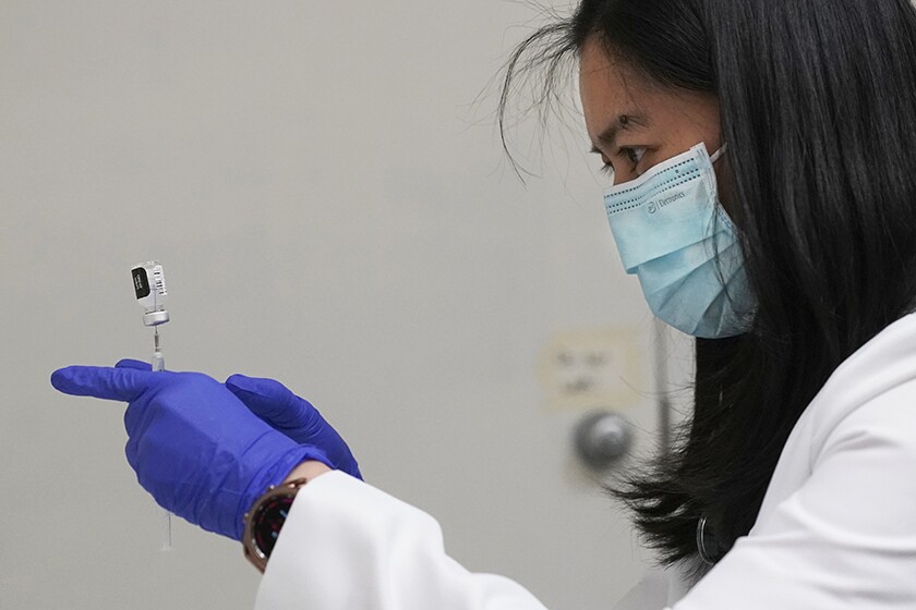 A female pharmacist holds a vaccine vial.