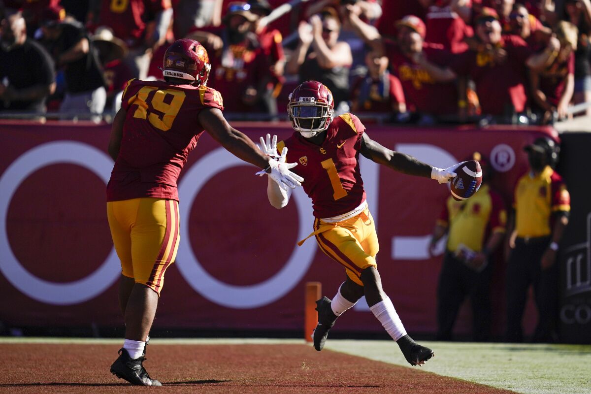 USC safety Greg Johnson, right, celebrates with defensive lineman Tuli Tuipulotu after returning an interception for a TD.