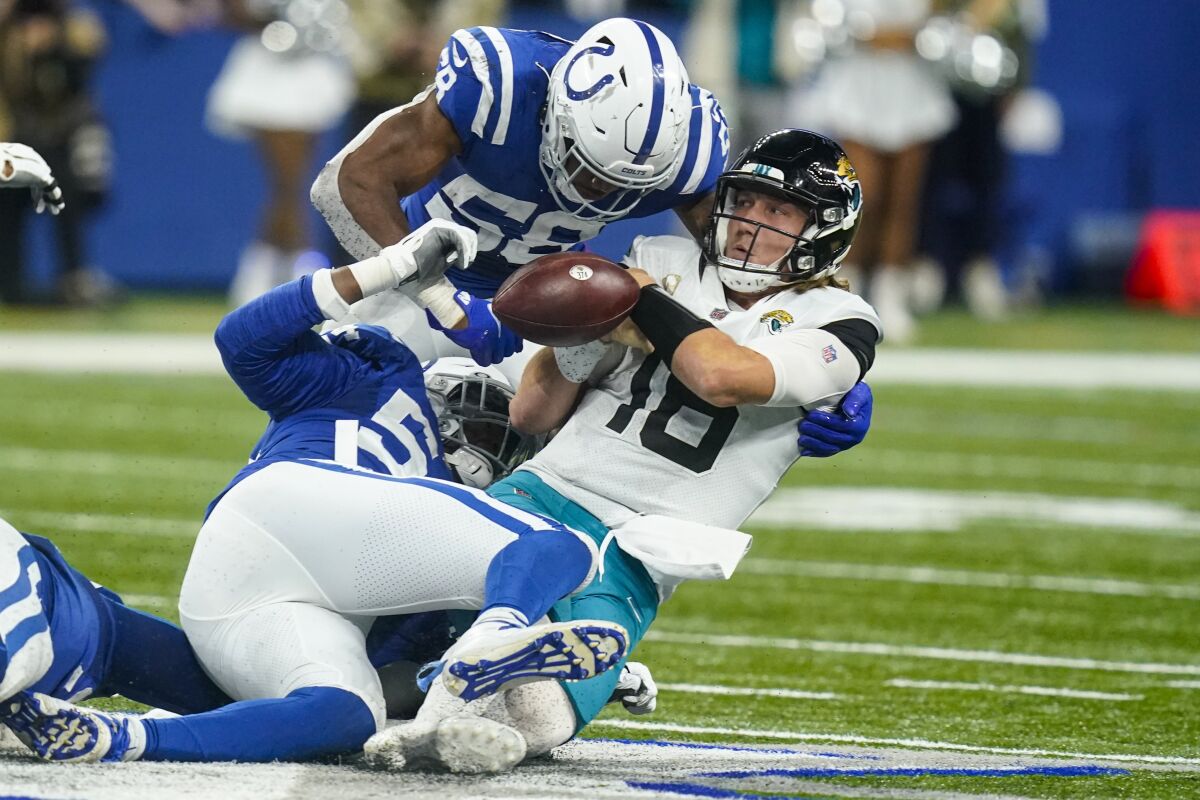 Jacksonville Jaguars quarterback Trevor Lawrence (16) fumbles the ball as he's hit by Indianapolis Colts middle linebacker Bobby Okereke (58) and defensive end Dayo Odeyingbo (54) in the second half of an NFL football game in Indianapolis, Sunday, Nov. 14, 2021. (AP Photo/Darron Cummings)