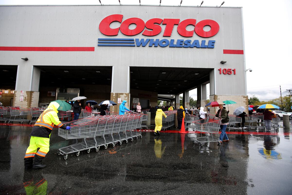 Employees push shopping carts in front of a Costco in Burbank.