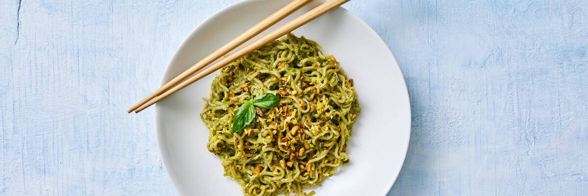 A bowl of pistachio pesto ramen with two chopsticks.