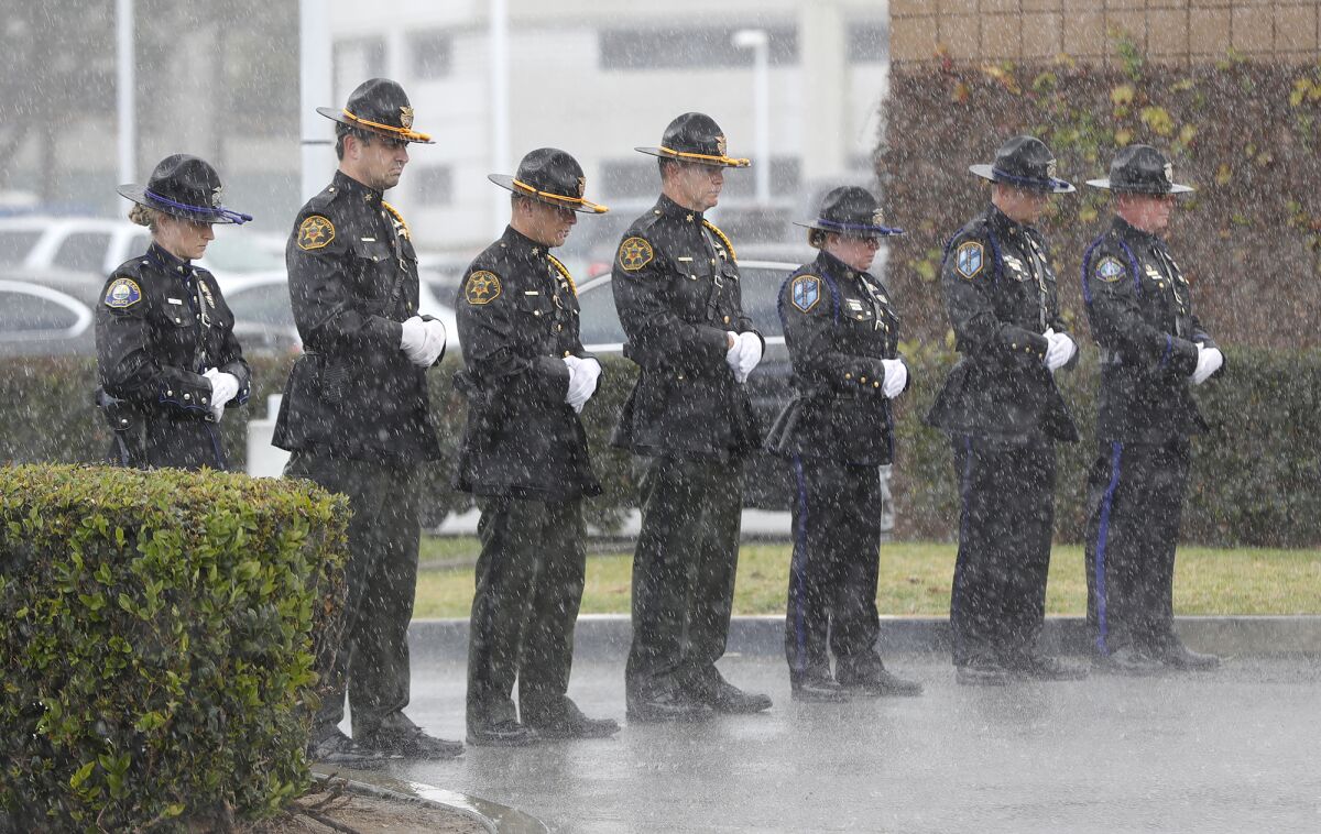A row of police officers in dress uniforms standing in the rain