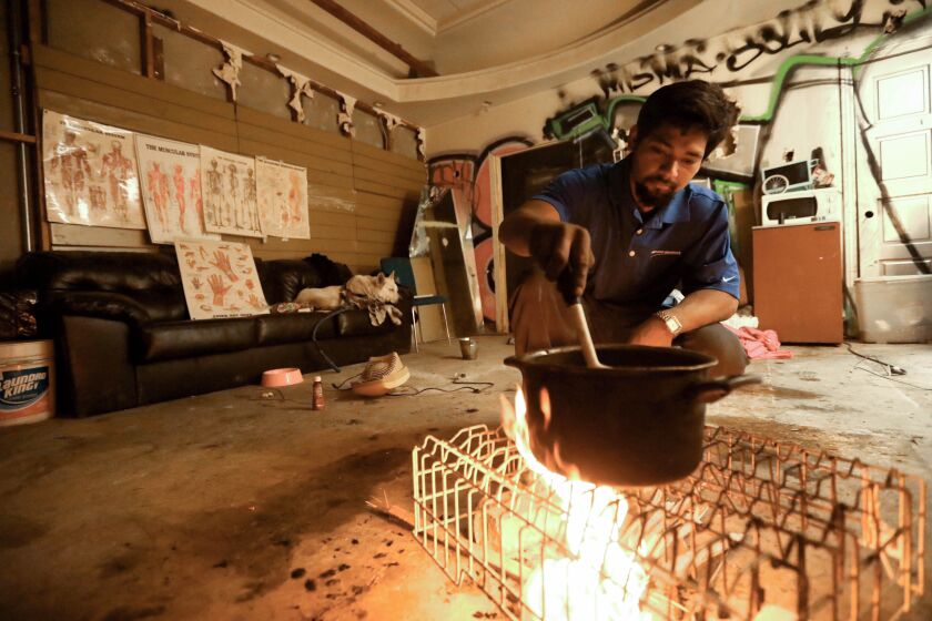 Alex Seijas-Torres cooks a meal in his room inside an abandoned building