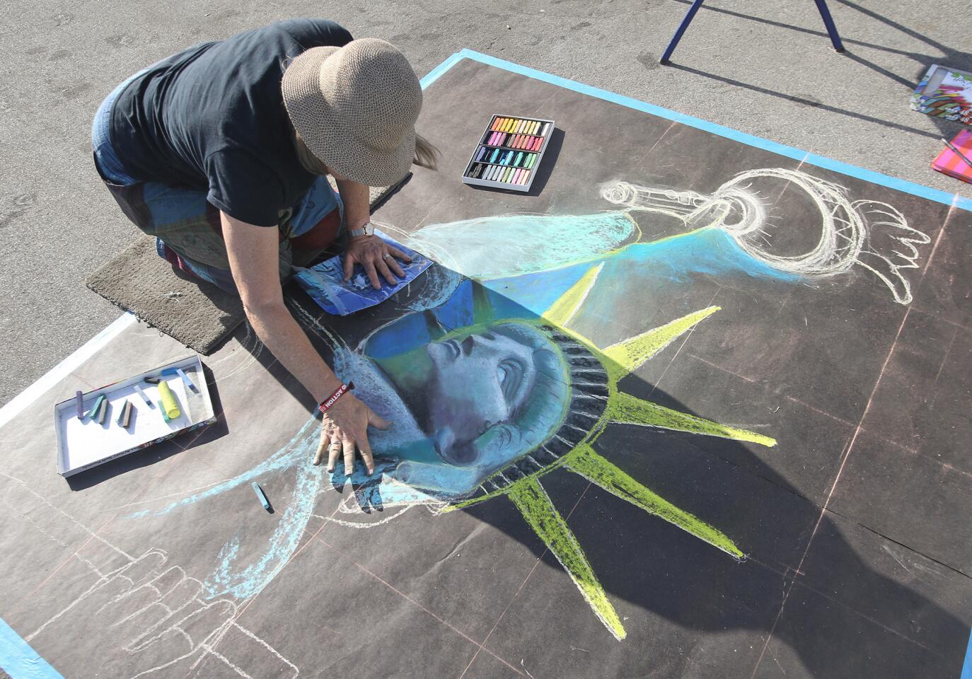 Chalk artist Maribeth McFaul creates a picture of the Statue of Liberty during the 2019 Costa Mesa Independence Day Party at the OC Fair and Events Center on Wednesday.
