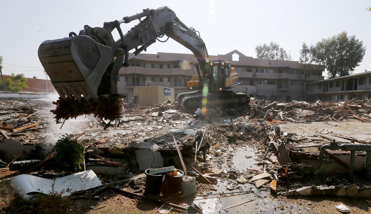 A heavy equipment operator demolishes the former Fiesta Motel in North Hollywood on Thursday. The motel served for 30 years as housing for some of the San Fernando Valley's homeless.