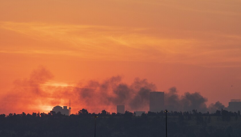 Smoke covers the Johannesburg skyline as people protests in downtown area, in Johannesburg, South Africa, Sunday, July 11, 2021. Protests have spread from the KwaZulu Natal province to Johannesburg against the imprisonment of former South African President Jacob Zuma who was imprisoned last week for contempt of court. (AP Photo/Themba Hadebe)