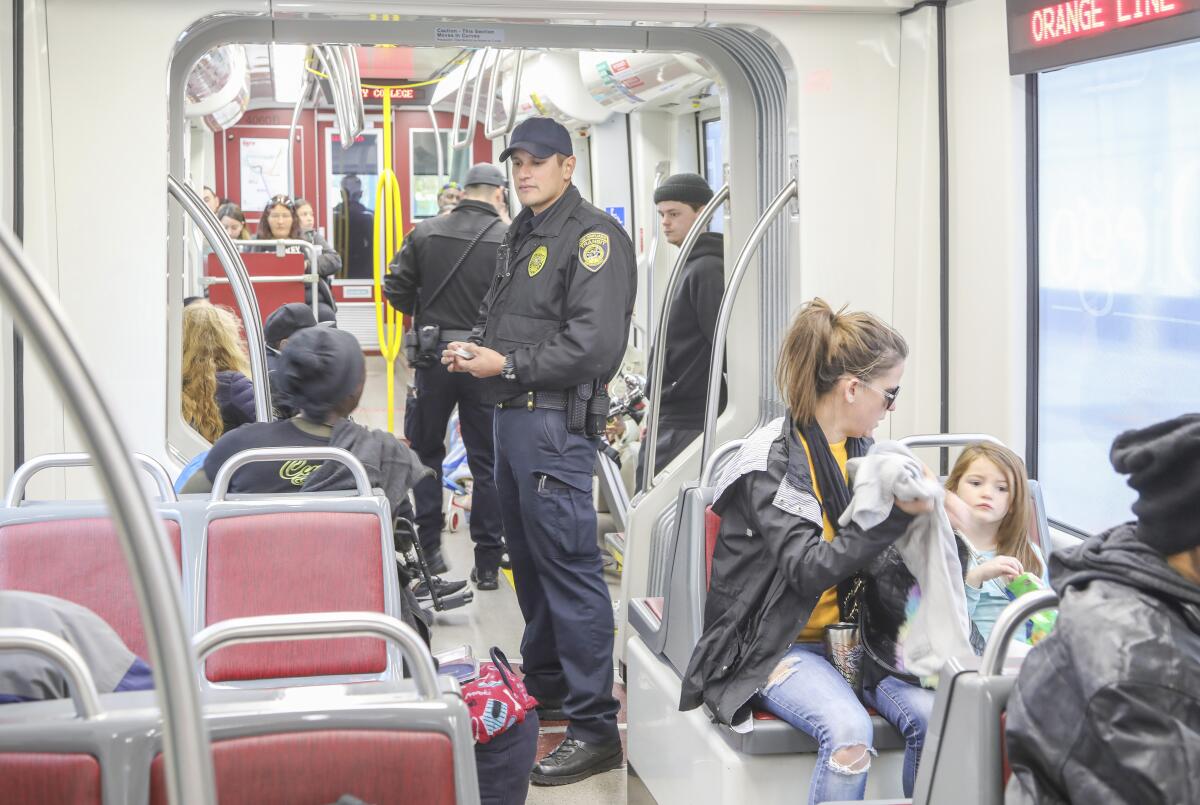 MTS transit officer Marc Vargas (middle) asks a woman to display a valid fare on the Orange Line.