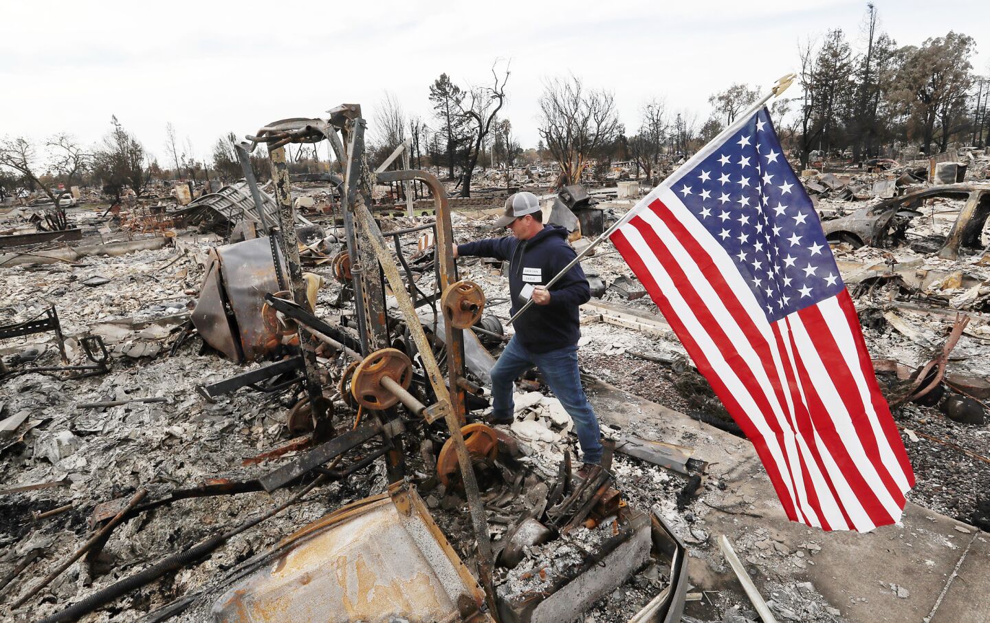 Jason Miller plants an American flag on the charred remains of his house as residents of Coffey Park return home.