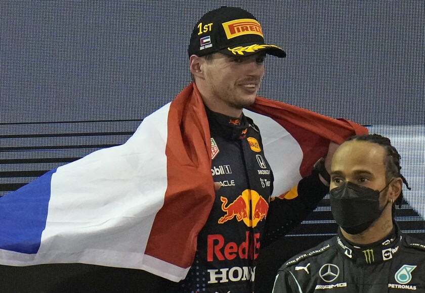 Red Bull driver Max Verstappen of the Netherlands celebrates after he became the world champion after winning the Formula One Abu Dhabi Grand Prix in Abu Dhabi, United Arab Emirates, Sunday, Dec. 12, 2021, On the right is second placed Mercedes driver Lewis Hamilton of Britain. (AP Photo/Hassan Ammar)