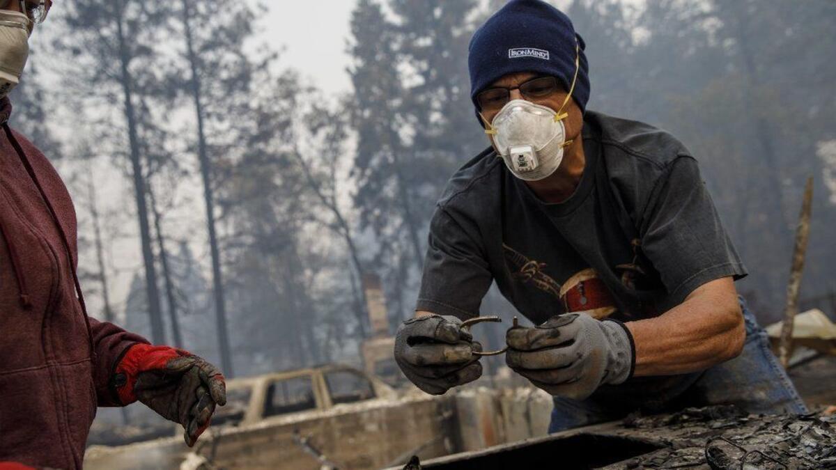 Michael John Ramirez recovers his wife's keepsake bracelet in the rubble of their destroyed home in Paradise, Calif.