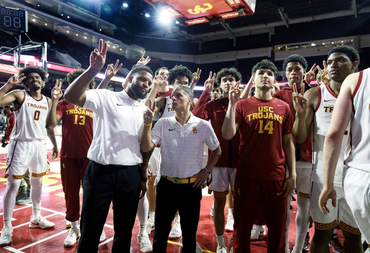 USC baş antrenörü Eric Musselman, yardımcı antrenör Will Conroy ve oyuncular zafer işareti için parmaklarını V şeklinde tutuyorlar.