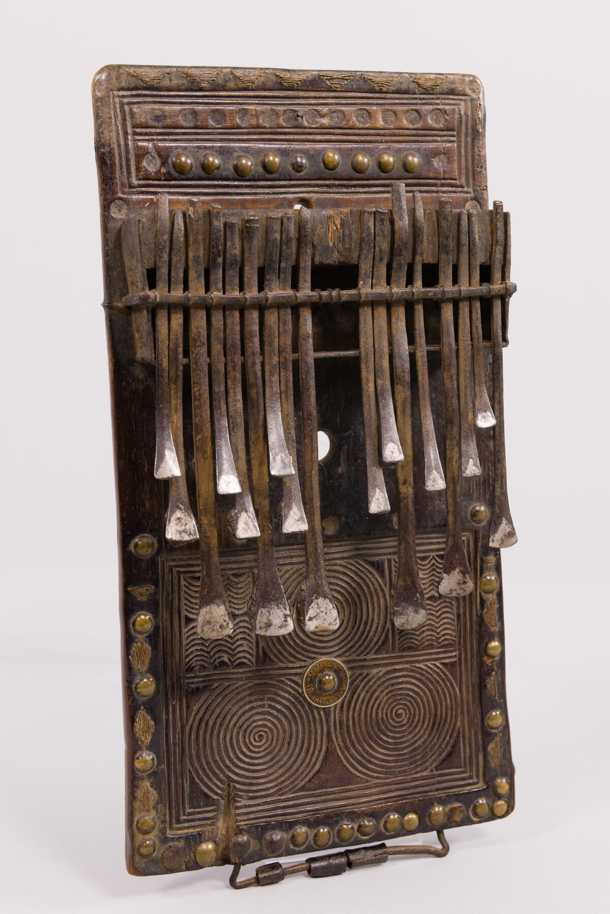 An African lamellophone features a wooden base with iron keys that are flicked with the finger to make music