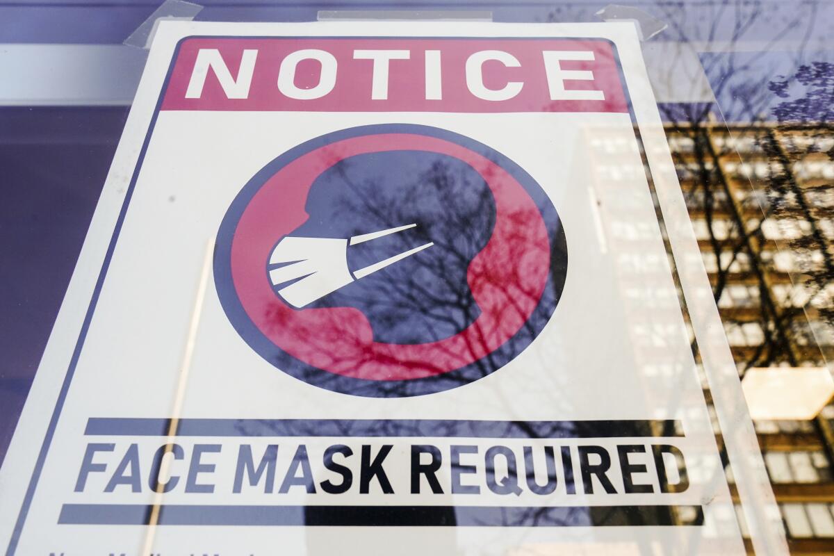 A sign reading "face mask required" with an image of a masked person 