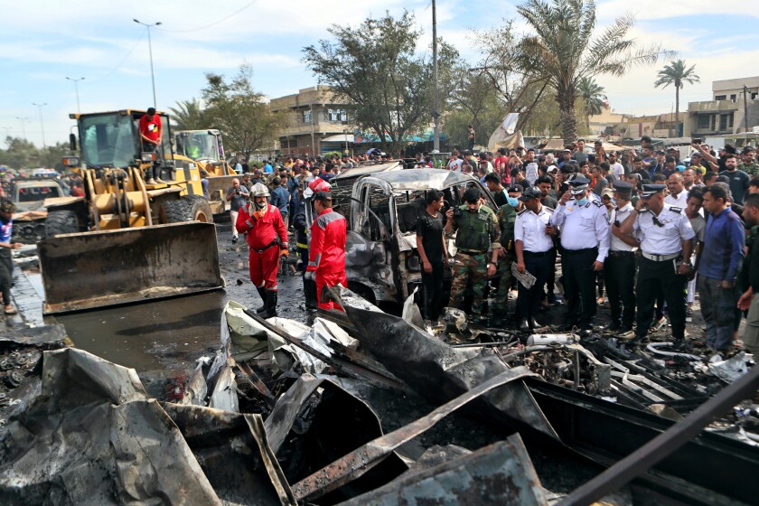 People and security forces inspect the scene of an explosion at a crowded outdoor used furniture market in Sadr City area, Iraq, Thursday, April 15, 2021. The powerful explosion rocked the market in east Baghdad on Thursday, killing at least one person and injuring many others, according to Iraq's military. The cause of the blast was not immediately known. (AP Photo/Khalid Mohammed)