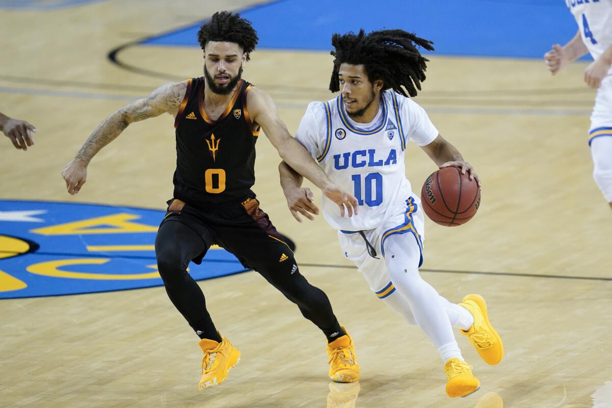 UCLA guard Tyger Campbell tries to drive past Arizona State guard Holland Woods.
