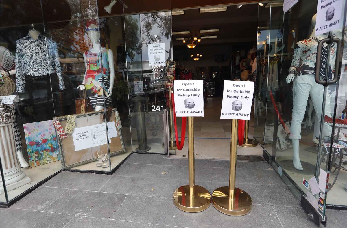 Two signs indicating curbside pickup only stand at the Violet Boutique in Laguna Beach as the second phase of reopening California began Friday.