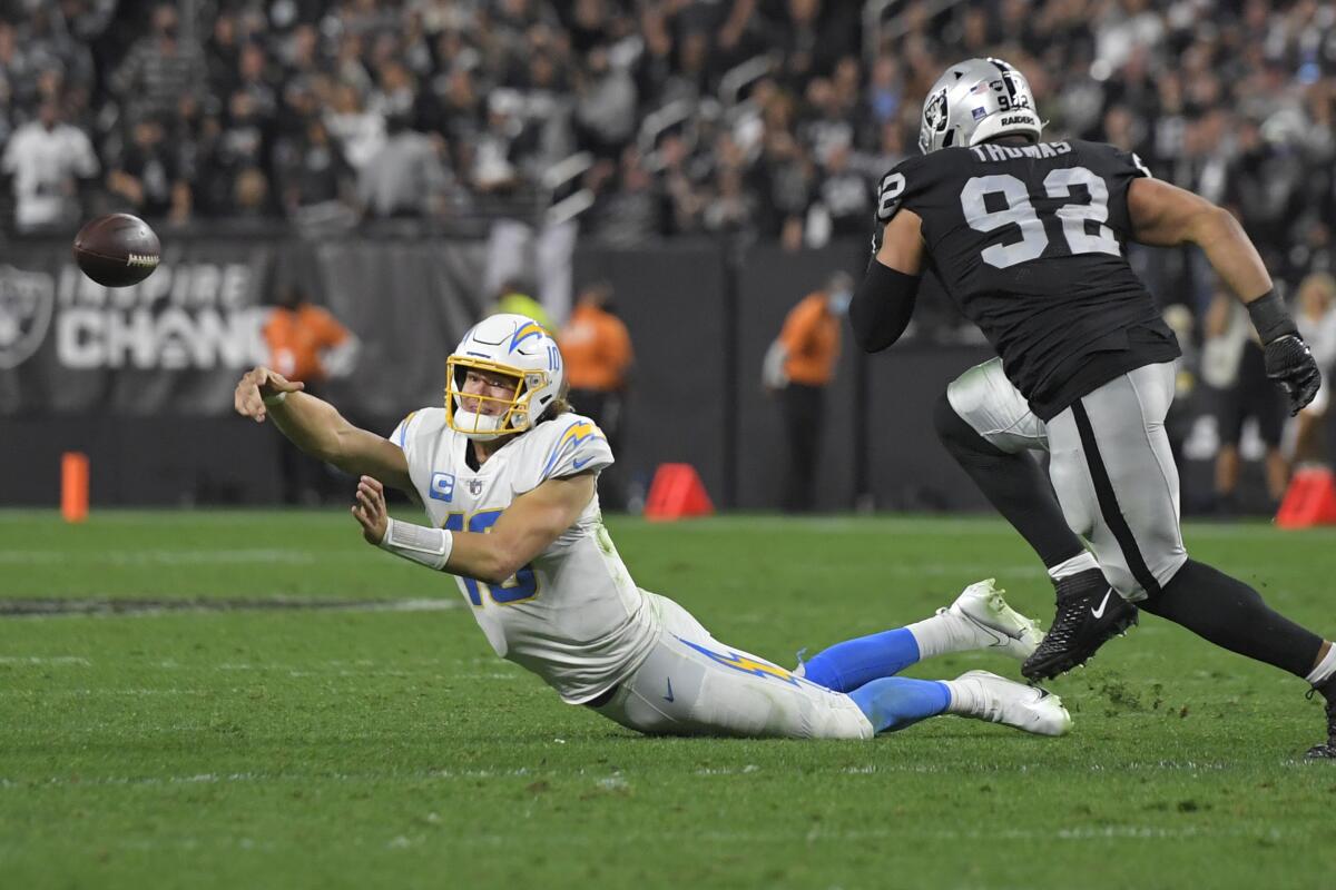 Chargers quarterback Justin Herbert attempts a throw on his way to the ground against the Raiders.