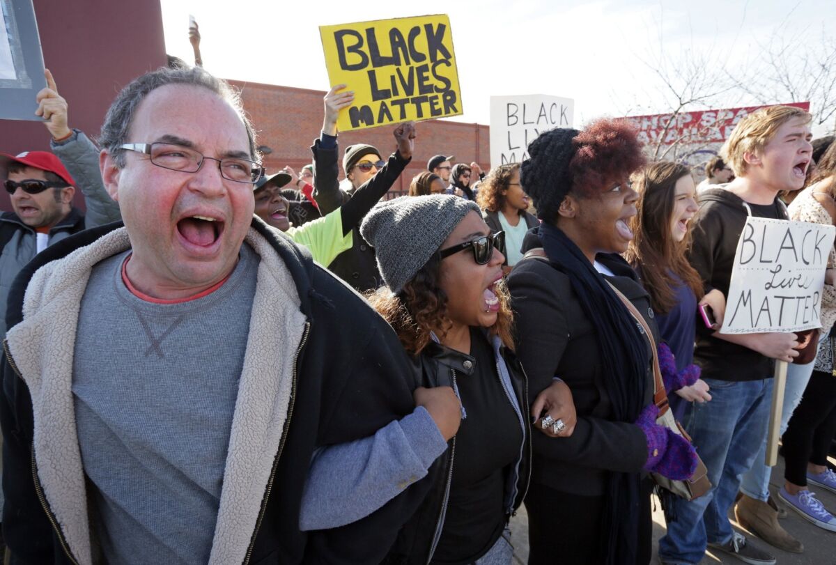 Protesters Daniel Conford, from left, Tracy Parks, Ashley Carter, Judy Lucas and Luke Davis shout "Black lives matter" as they face police in Ferguson, Mo., last year.