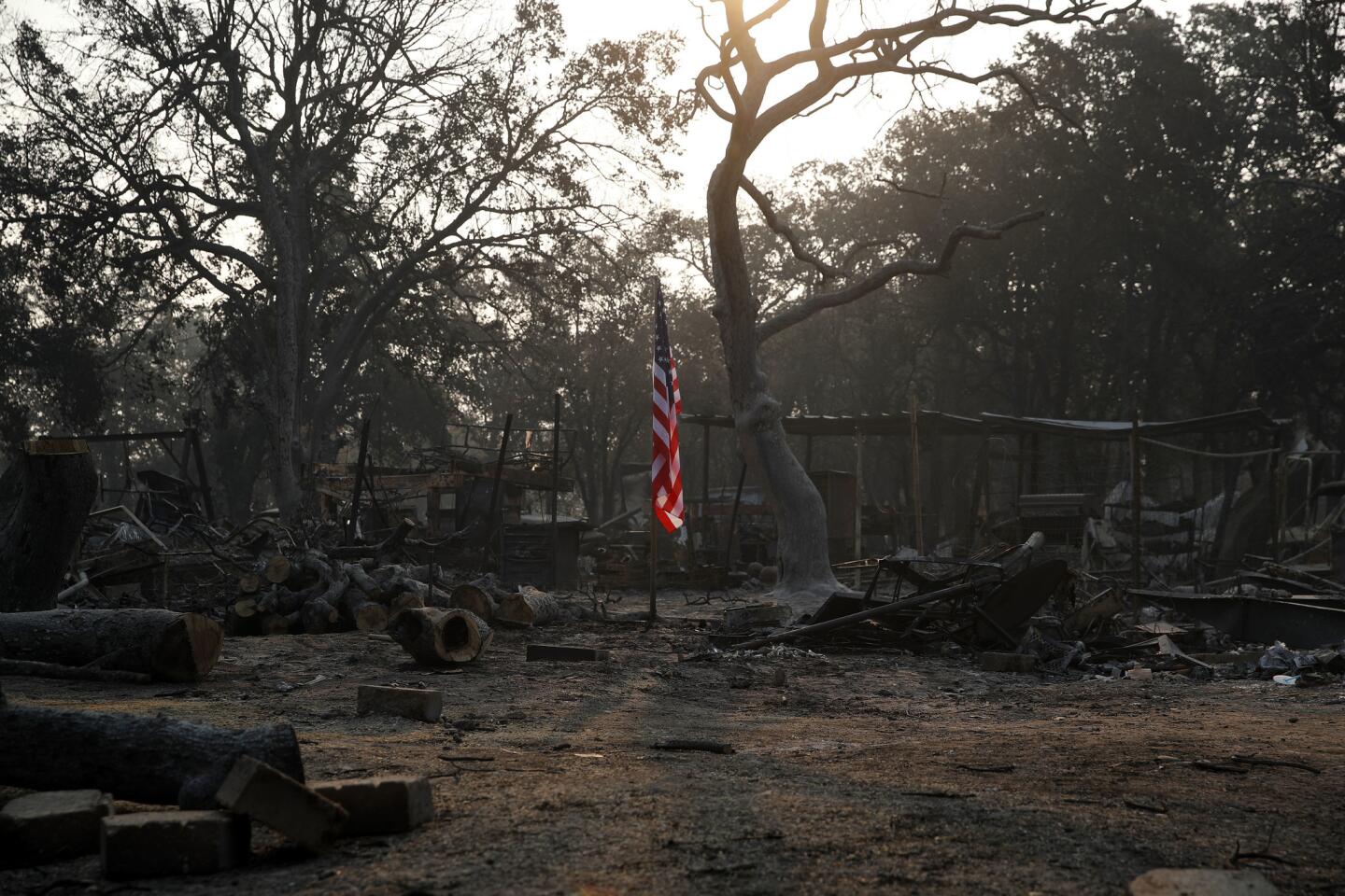 A flag flies in the charred rubble of a home on Aug. 11, 2018, in Redding, Calif.