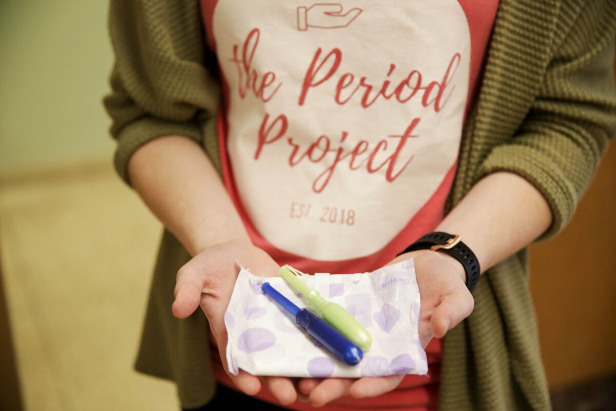 A Period Project member  holds out an assortment of menstrual care products Feb. 6, 2020.