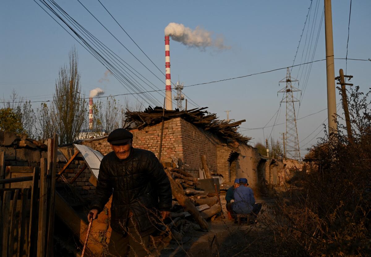 A coal-fueled power station in China, with a smokestack on a hill and surrounded by power transmission lines.