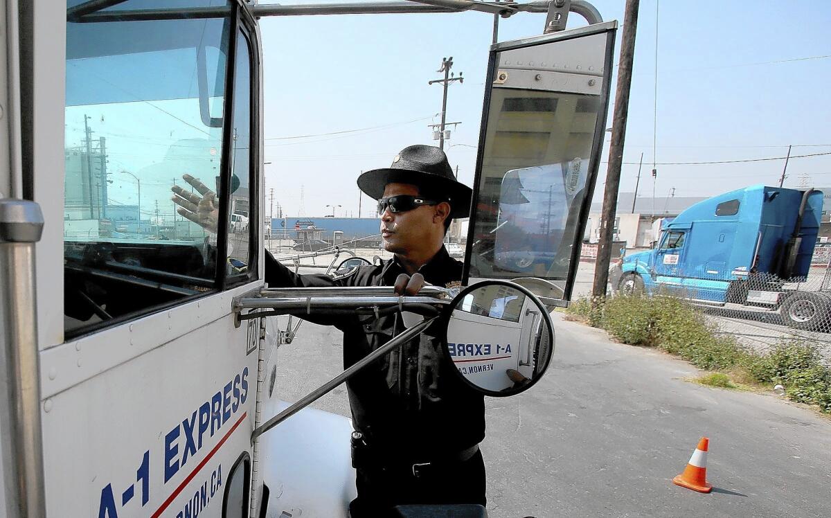 Air Resources Board Inspector Jose Andujar puts a sticker on the windsheild of a truck that passed an inspection for possible air pollution violations at a checkpoint in Boyle Heights.
