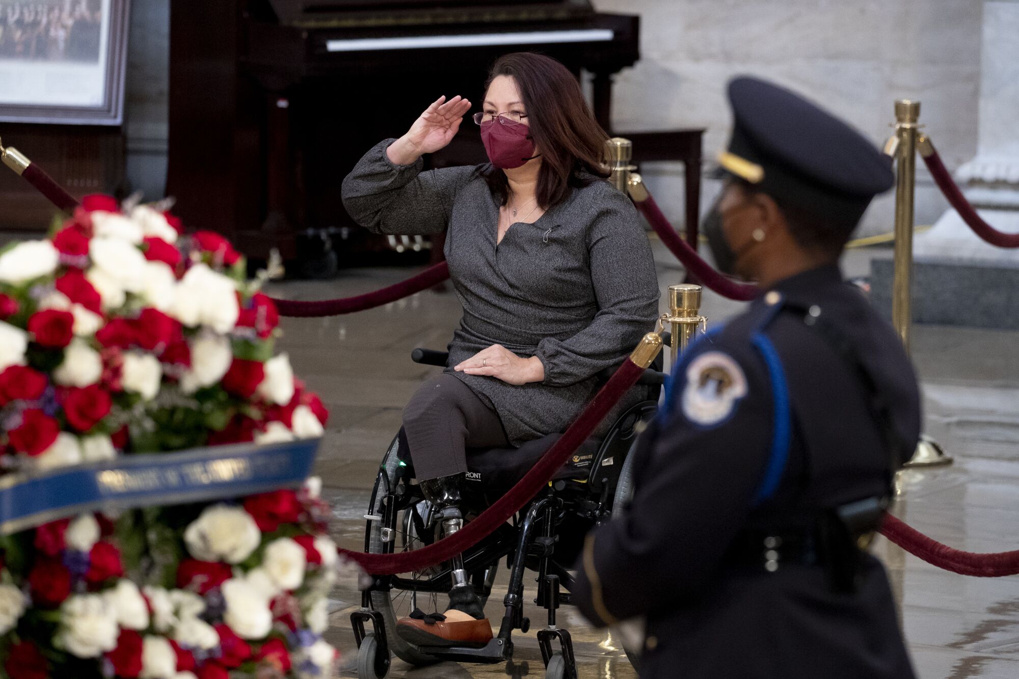 A woman seated in a wheelchair salutes the casket of Sen. Bob Dole.