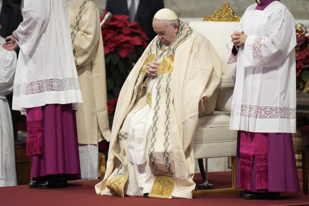 Pope Francis sits with his head bowed and hands folded while wearing vestments during a special New Year's Day Mass.