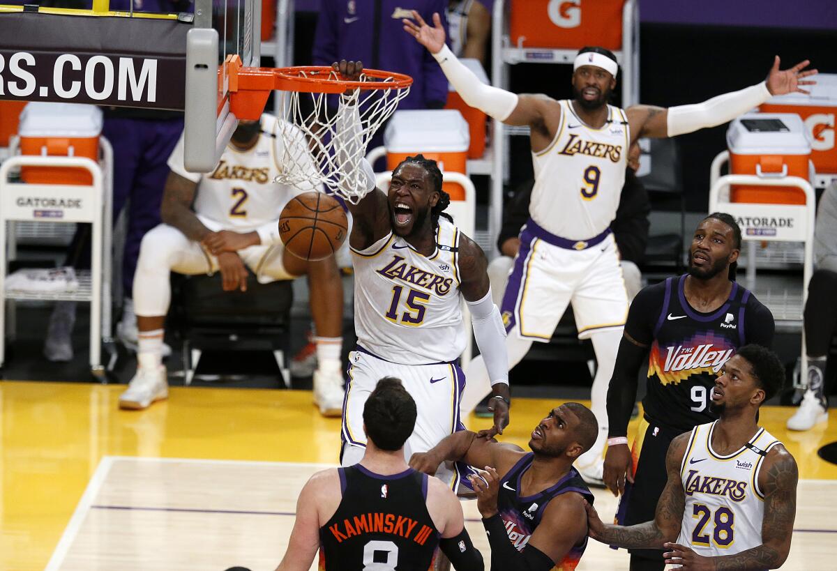 Lakers center Montrezl Harrell dunks over Phoenix Suns guard Chris Paul and forward Frank Kaminsky.